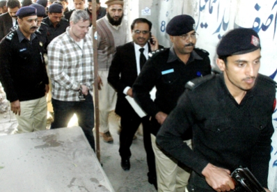 Pakistani security officials escort a U.S. consulate employee, who has not been named by US authorities, second from left, at a local court in Lahore, Pakistan on Friday, Jan. 28, 2011. Pakistan will pursue murder charges against the employee suspected of shooting two armed men during a possible robbery attempt, a top prosecutor said. (AP Photo/Hamza Ahmed)